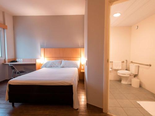 ibis Presidente Prudente Manoel Goulart في برزيدنتي برودينتي: غرفة نوم بسرير وحمام مع مرحاض