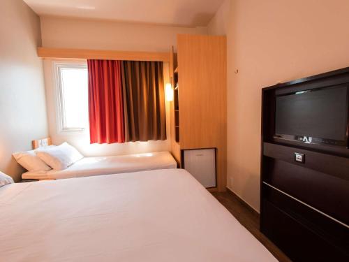 a hotel room with a bed and a flat screen tv at ibis Presidente Prudente Manoel Goulart in Presidente Prudente