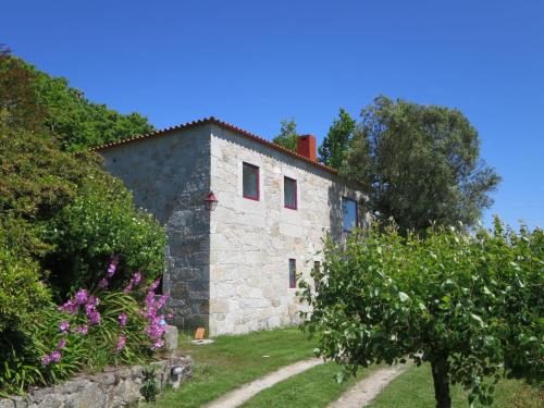 una antigua casa de piedra con jardín y flores en Holiday Home De Pedral by Interhome en Castelo do Neiva