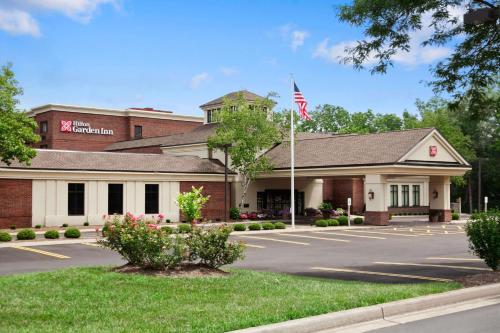 a building with an american flag in a parking lot at Hilton Garden Inn Rochester/Pittsford in Bushnell Basin