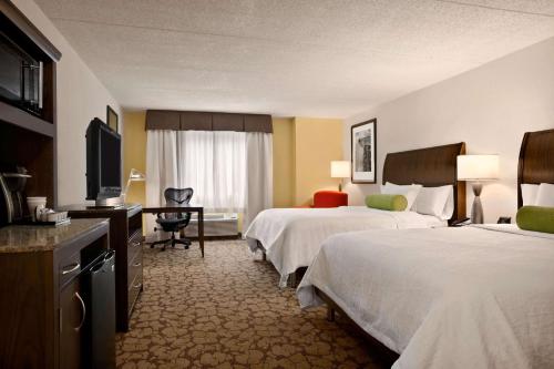 a hotel room with two beds and a television at Hilton Garden Inn Rochester/Pittsford in Bushnell Basin