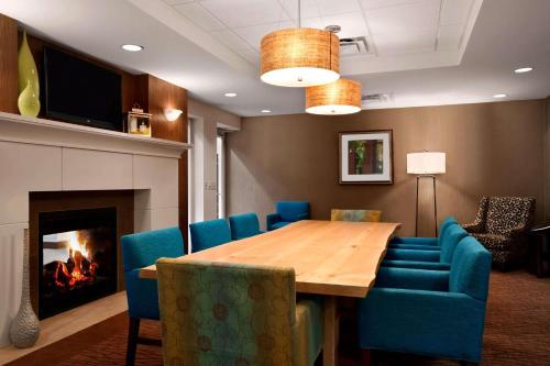 a dining room with a table and chairs and a fireplace at Hilton Garden Inn Rochester/Pittsford in Bushnell Basin