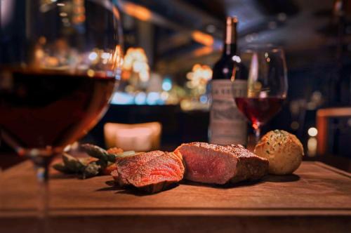 a table with a glass of wine and some meat at Grand Hyatt Hong Kong in Hong Kong