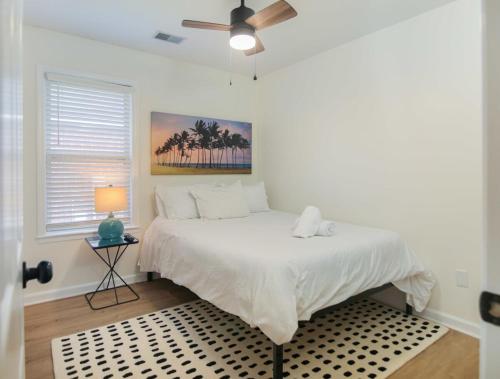 um quarto com uma cama branca e uma ventoinha de tecto em Renovated Charleston Oasis Mins to Dtwn and Beach em Charleston