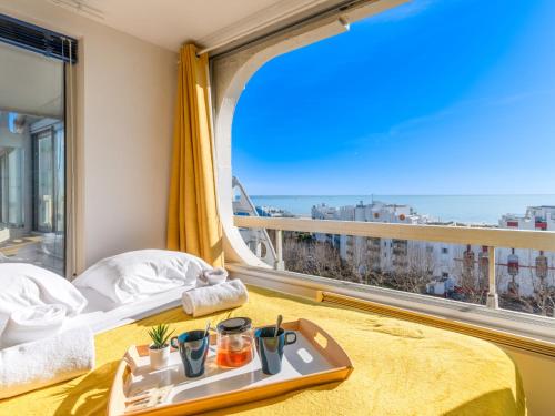 Habitación de hotel con bandeja de comida en una cama con ventana grande en Apartment Les Marines de Haute-Plage-5 by Interhome, en La Grande-Motte