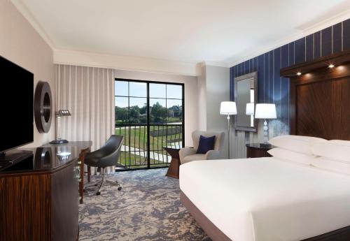 Hilton Dallas/Rockwall Lakefront Hotel في روكوول: غرفه فندقيه بسرير وشرفه