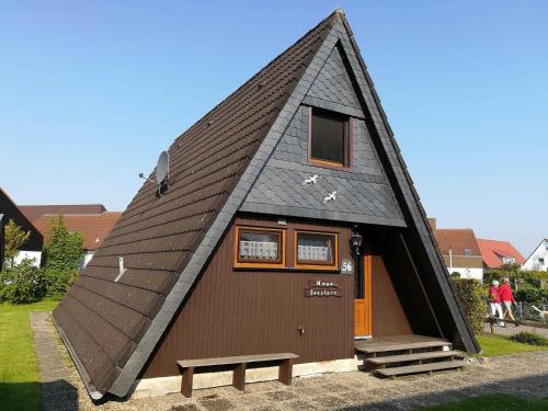 una casa con techo triangular y un banco delante en Ferienhaus Seestern, en Carolinensiel