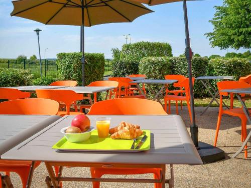 un plato de comida en una mesa con una sombrilla en ibis budget Saint Lô, en Saint Lo