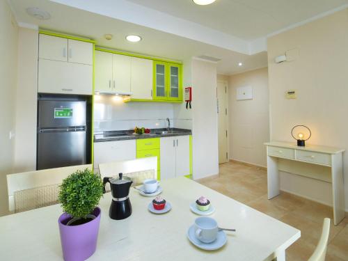 een keuken met gele kasten en een witte tafel en stoelen bij Apartment Esmeralda Suites-2 by Interhome in Calpe