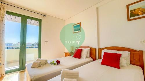 dwa łóżka w pokoju z dwoma oknami w obiekcie Aquamar Sunset T2 by HsR Marina Vilamoura w mieście Quarteira
