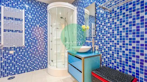 W wyłożonej niebieskimi kafelkami łazience znajduje się umywalka i prysznic. w obiekcie Aquamar Sunset T2 by HsR Marina Vilamoura w mieście Quarteira