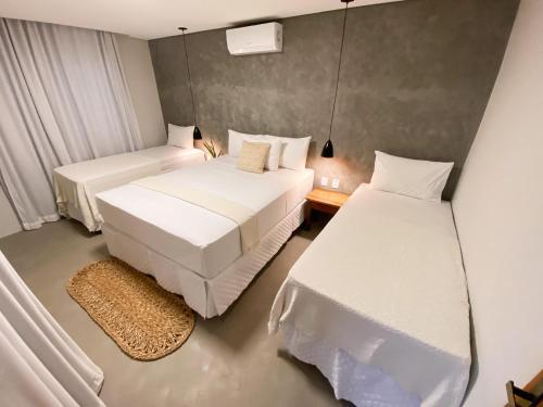 2 bedden in een kleine kamer met witte lakens bij Pousada Baobá in Jericoacoara