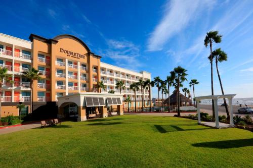 a hotel with palm trees in front of a park at DoubleTree by Hilton Galveston Beach in Galveston