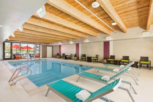 a pool in a hotel with chairs and tables at Home2 Suites by Hilton Farmington/Bloomfield in Farmington