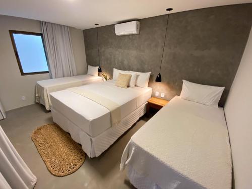 a hotel room with two beds and a window at Pousada Baobá in Jericoacoara