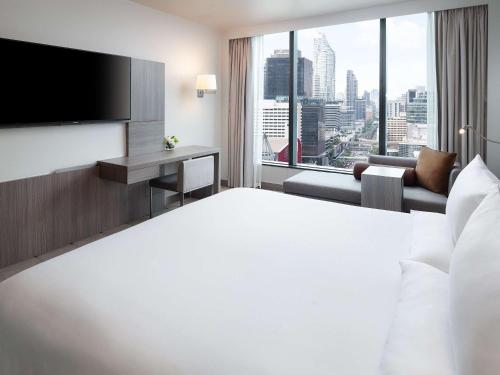 バンコクにあるNovotel Bangkok Platinum Pratunamの大きなベッドと大きな窓が備わるホテルルームです。
