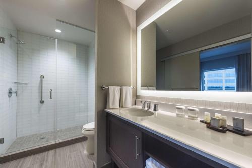 a bathroom with a sink and a toilet and a mirror at Embassy Suites by Hilton The Woodlands in The Woodlands