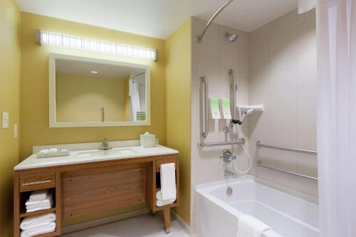 a bathroom with a tub and a sink and a mirror at Home2 Suites by Hilton Fort Smith in Fort Smith