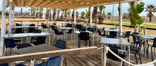 un restaurant avec des tables et des chaises sur une terrasse en bois dans l'établissement Pensión La Ola, à Grao de Castellón