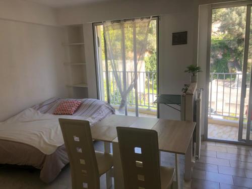 Schlafzimmer mit einem Bett und einem Tisch sowie einem Balkon in der Unterkunft Magnifique studio cœur de Nice in Nizza