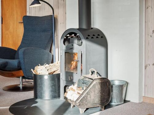 a wood burning stove in a room with a chair at Holiday Home Avelin - 800m from the sea in NW Jutland by Interhome in Torsted