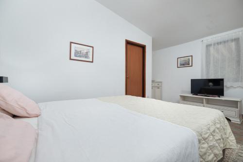 a white bedroom with a bed and a television at St. Bečić in Poreč