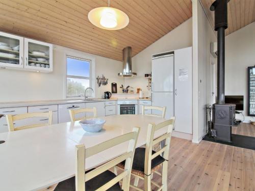 uma cozinha com uma mesa e cadeiras e um frigorífico em Holiday Home Florida - 100m from the sea in NW Jutland by Interhome em Lokken