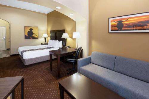 a hotel room with a bed and a couch at La Quinta by Wyndham Houston New Caney in New Caney
