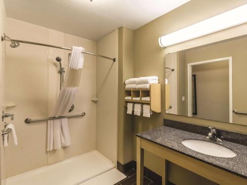a bathroom with a sink and a shower and a mirror at La Quinta by Wyndham Fargo-Medical Center in Fargo