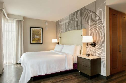 a bedroom with a large white bed and a night stand at Embassy Suites By Hilton Berkeley Heights in Berkeley Heights