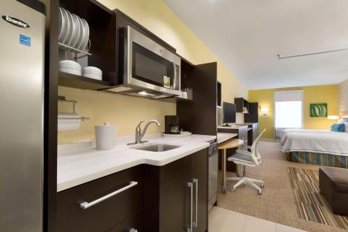 a kitchen with a sink and a room with a bed at Home2 Suites by Hilton Houston Pasadena in Pasadena