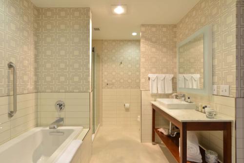 a bathroom with a tub and a sink at The Lismore Hotel Eau Claire - a DoubleTree by Hilton in Eau Claire