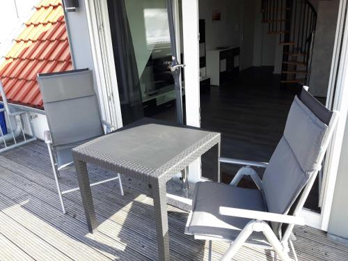 - une table et deux chaises sur une terrasse couverte dans l'établissement Ferienwohnung Claudia, à Carolinensiel