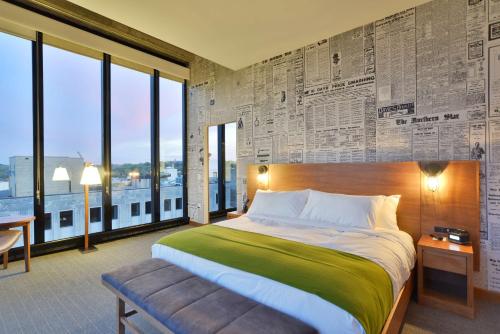 a bedroom with a large bed and large windows at The Lismore Hotel Eau Claire - a DoubleTree by Hilton in Eau Claire