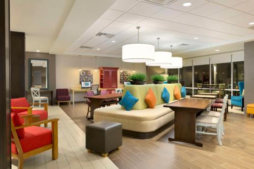 eine Lobby mit einem Sofa, Tischen und Stühlen in der Unterkunft Home2 Suites by Hilton Houston Willowbrook in Houston