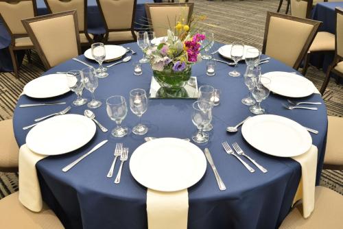 a table with plates and glasses and a vase of flowers at The Lismore Hotel Eau Claire - a DoubleTree by Hilton in Eau Claire