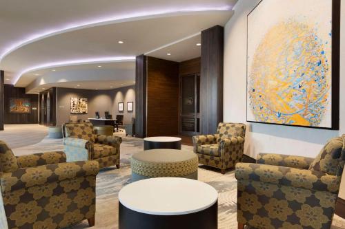 a lobby with chairs and tables and a painting at Embassy Suites by Hilton Greenville Downtown Riverplace in Greenville