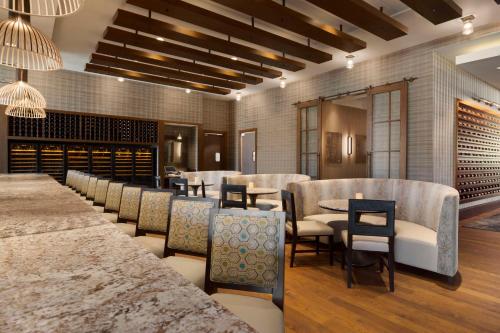 een restaurant met tafels en stoelen en wijnflessen bij Embassy Suites by Hilton Greenville Downtown Riverplace in Greenville