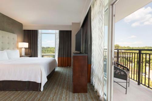 a hotel room with a bed and a balcony at Embassy Suites by Hilton Greenville Downtown Riverplace in Greenville