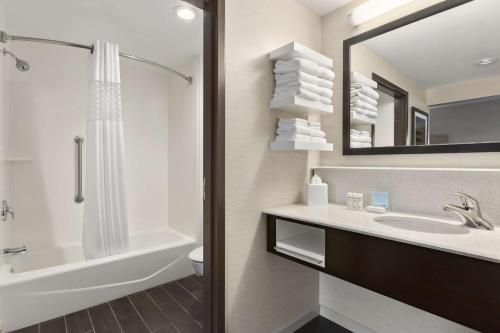 a bathroom with a sink and a tub and a mirror at Hampton Inn Penn Yan, NY in Penn Yan