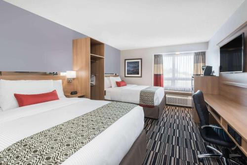 a hotel room with two beds and a flat screen tv at Microtel Inn & Suites by Wyndham Sudbury in Sudbury