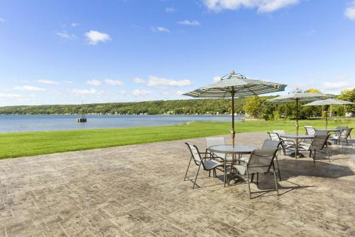 a group of tables and chairs with umbrellas and a lake at Hampton Inn Penn Yan, NY in Penn Yan