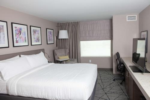 a hotel room with a white bed and a desk at Hilton Garden Inn Springfield in Springfield