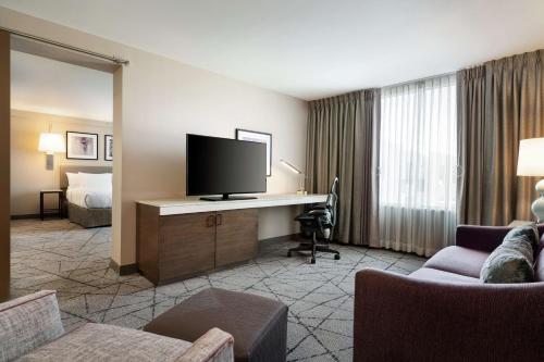 a hotel room with a desk with a television and a bed at Hilton Garden Inn Springfield in Springfield