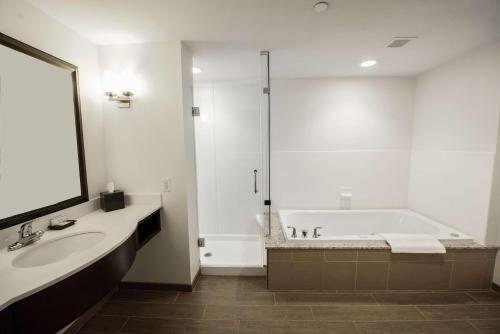 Baño blanco con bañera y lavamanos en Hilton Garden Inn Indiana at IUP en Indiana
