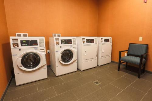 a laundry room with four washing machines and a chair at Hilton Garden Inn Indiana at IUP in Indiana