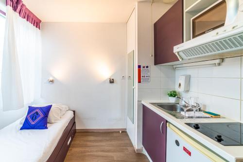 a small kitchen with a couch in a room at Montempô Apparthôtel Lyon Viviani in Vénissieux