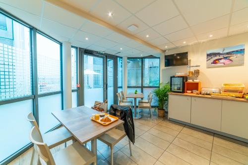 a kitchen with a table and chairs and windows at Montempô Apparthôtel Lyon Viviani in Vénissieux