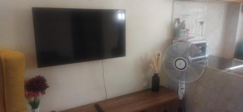 a flat screen tv hanging on a wall with a fan at Belch 105 Apartment in Kisumu