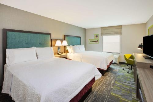 a hotel room with two beds and a flat screen tv at Hampton Inn & Suites By Hilton, Southwest Sioux Falls in Sioux Falls